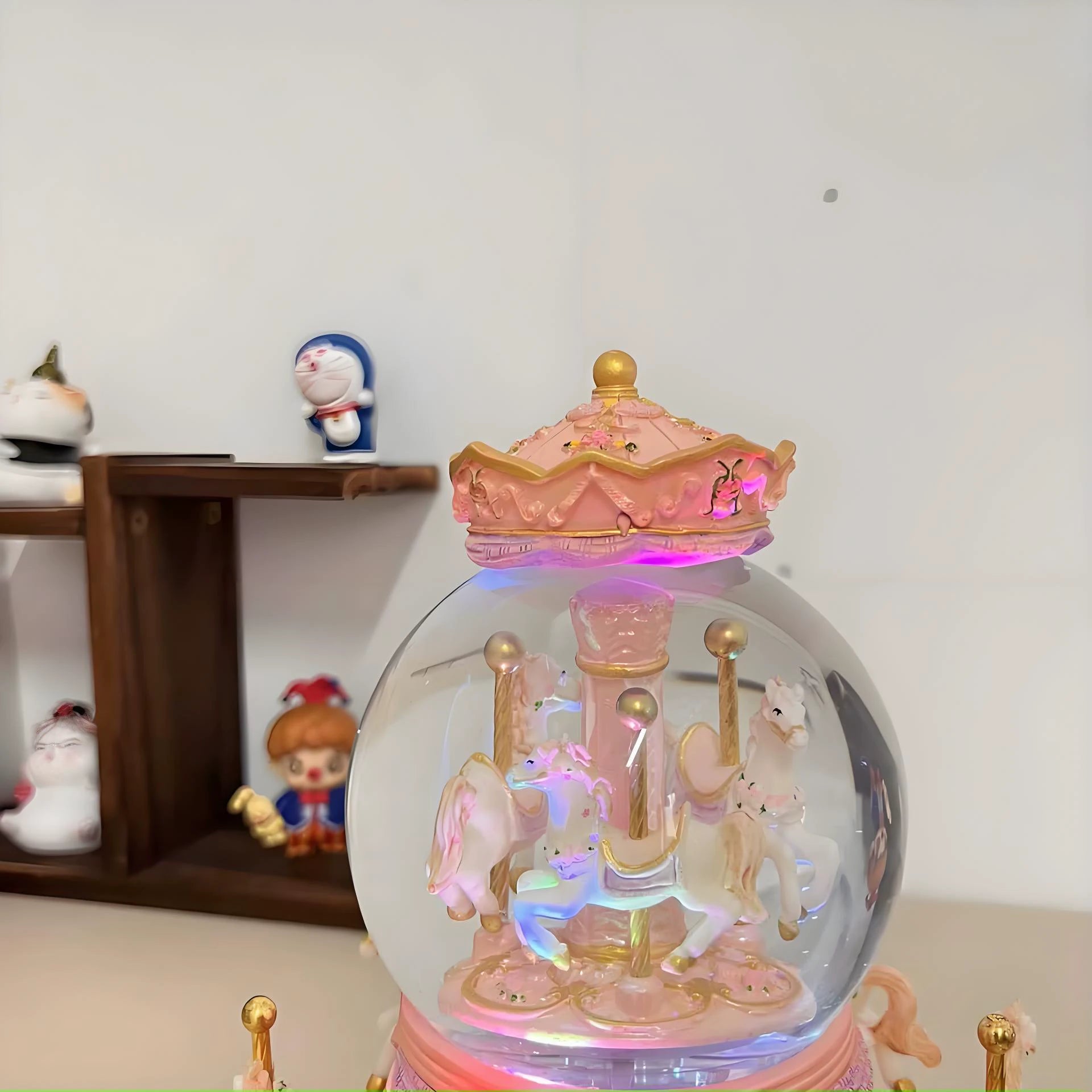 Decorative snow globe with carousel horses and colorful lights on a shelf.