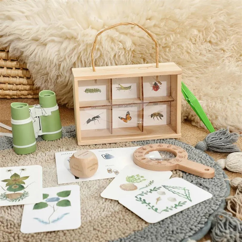 Educational nature set with wooden box, cards, and tools on a soft surface
