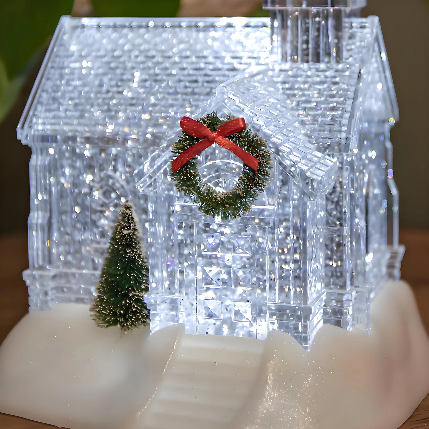 Crystal clear Christmas village house with a wreath and tree on a wooden surface
