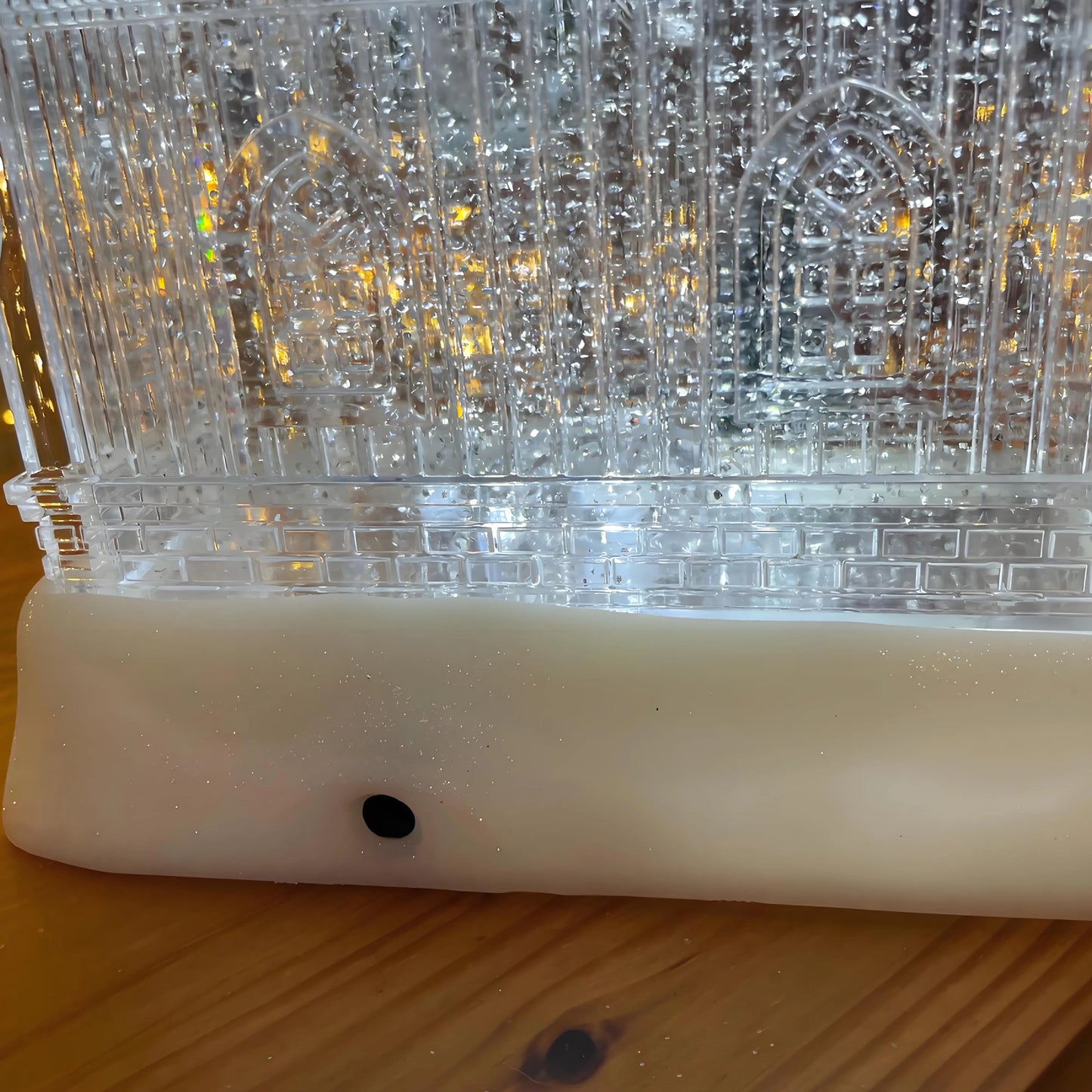 Close-up of a clear plastic object with a white base on a wooden surface