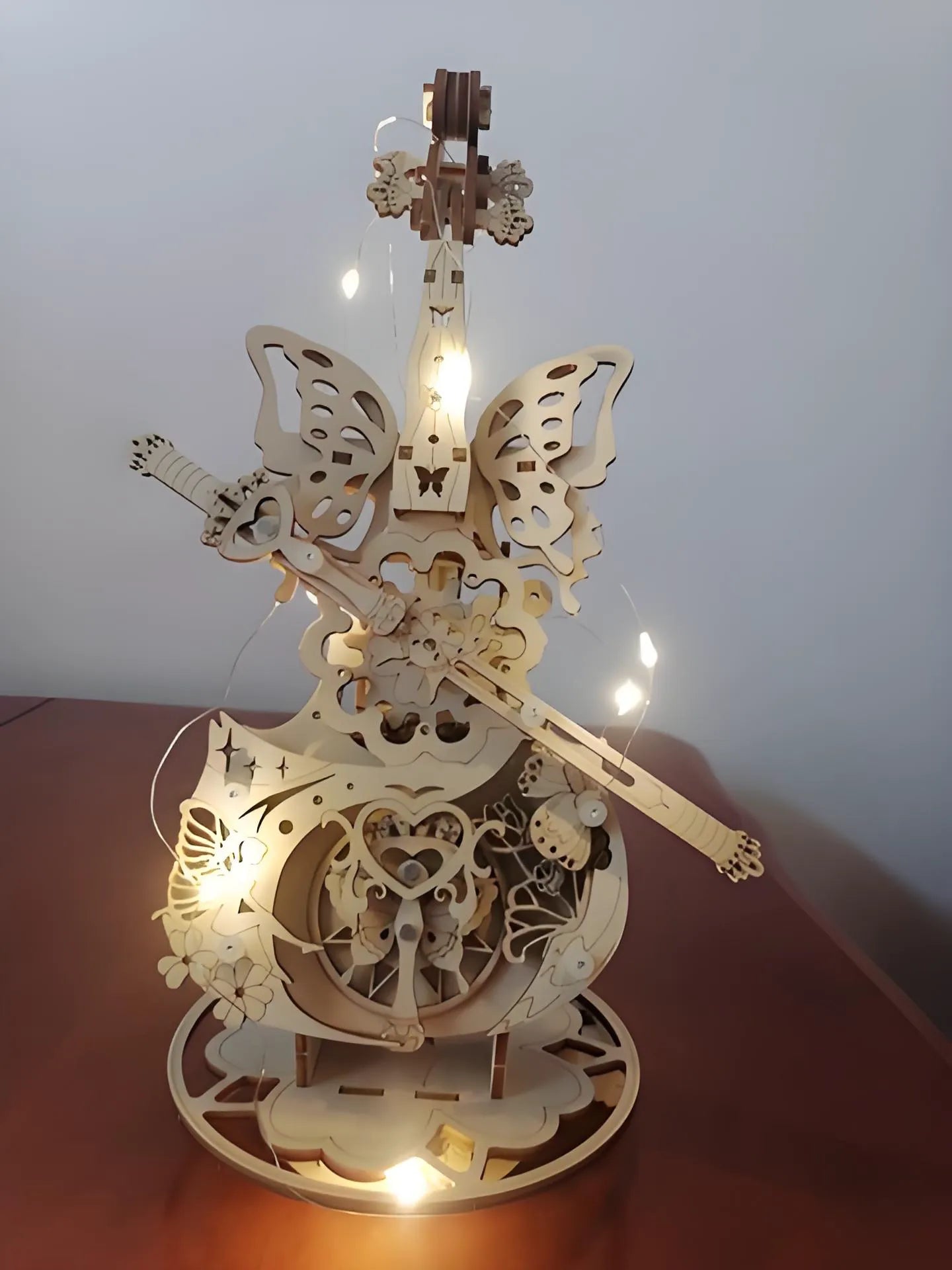 Wooden mechanical model with gears and butterfly designs on a white background
