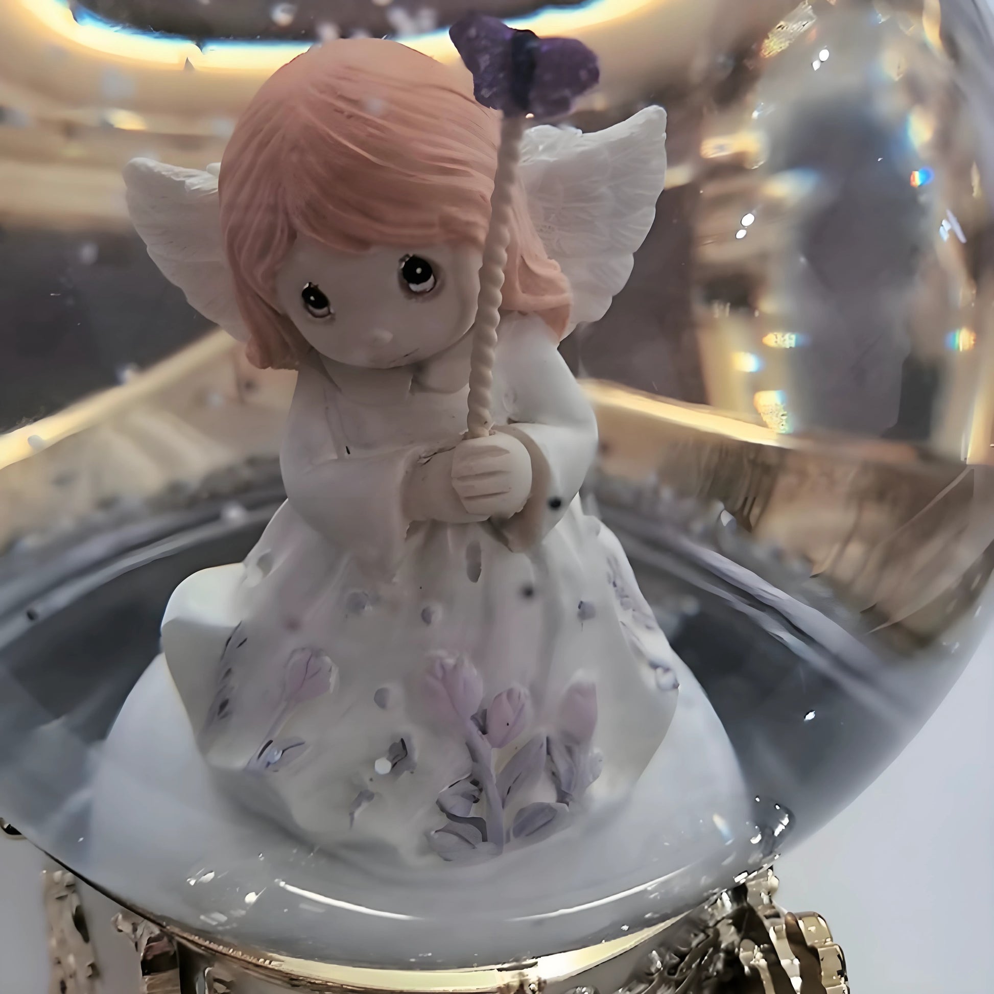 Decorative angel figurine with pink hair and white dress inside a glass display case.