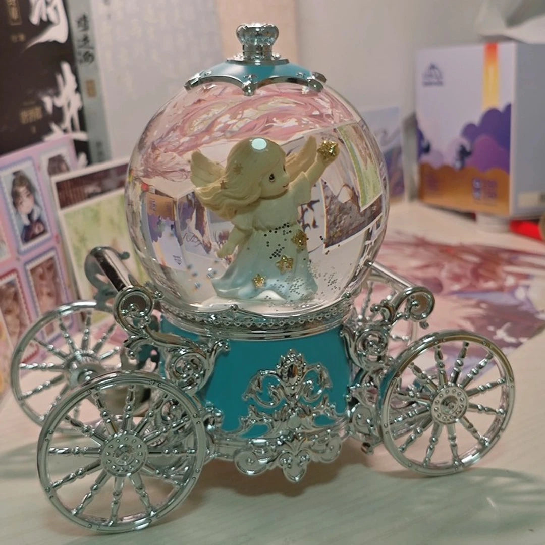 Decorative angel figurine in a glass ball with a carriage base on a table.