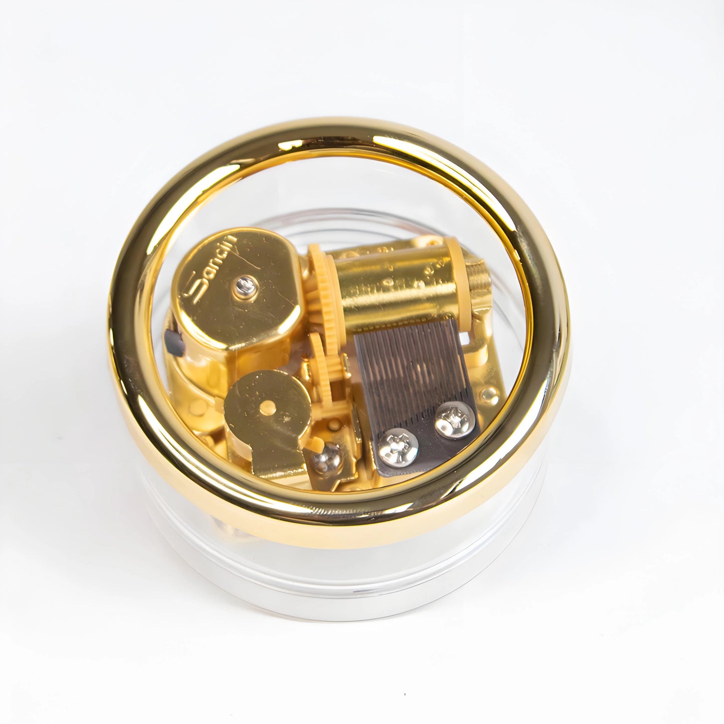 Vintage mini wind-up music box with clear acrylic shell showing gold-plated mechanical movement
