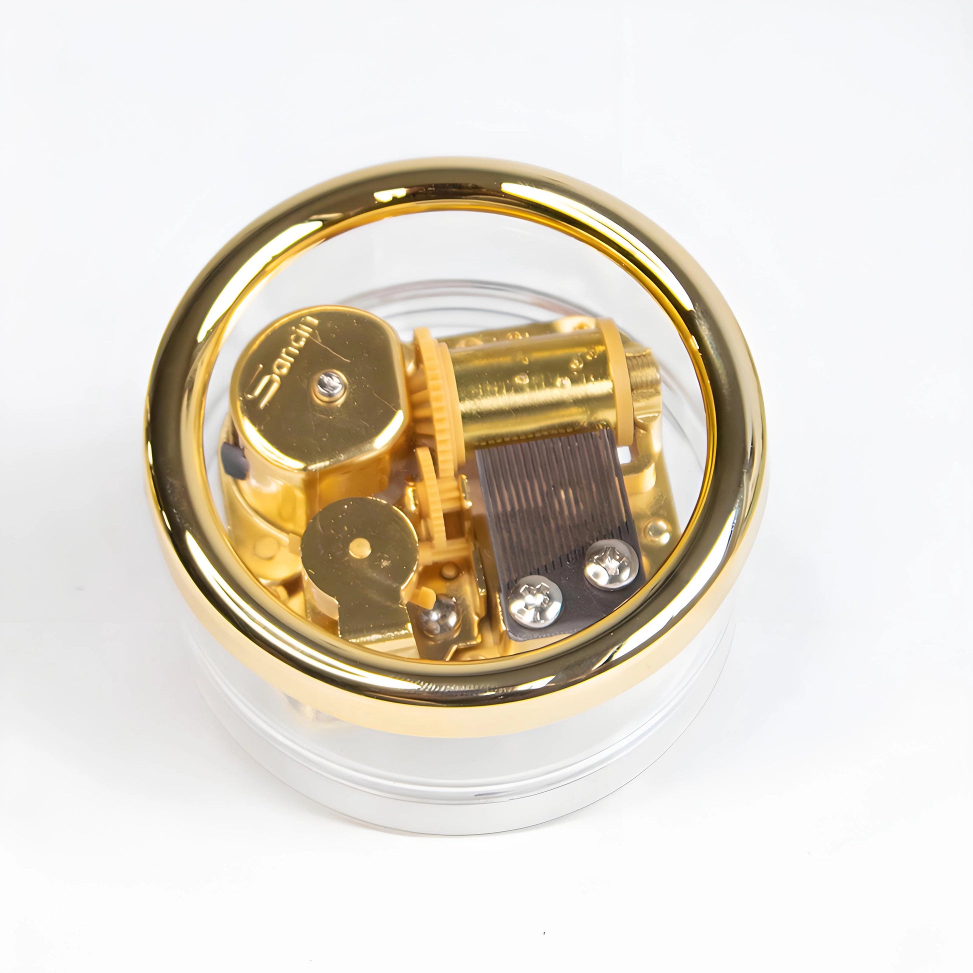 Vintage mini wind-up music box with clear acrylic shell showing gold-plated mechanical movement