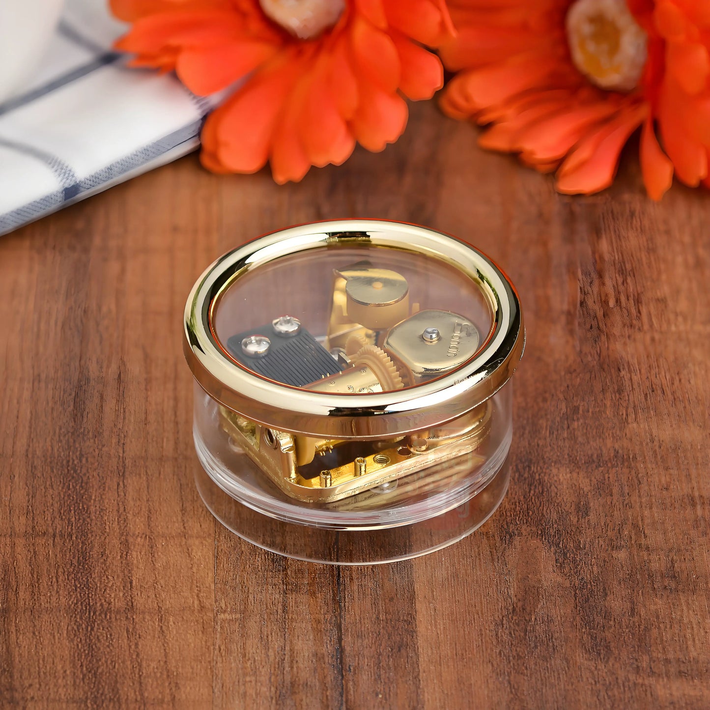 Vintage mini wind-up music box with clear acrylic shell showing gold-plated mechanical movement