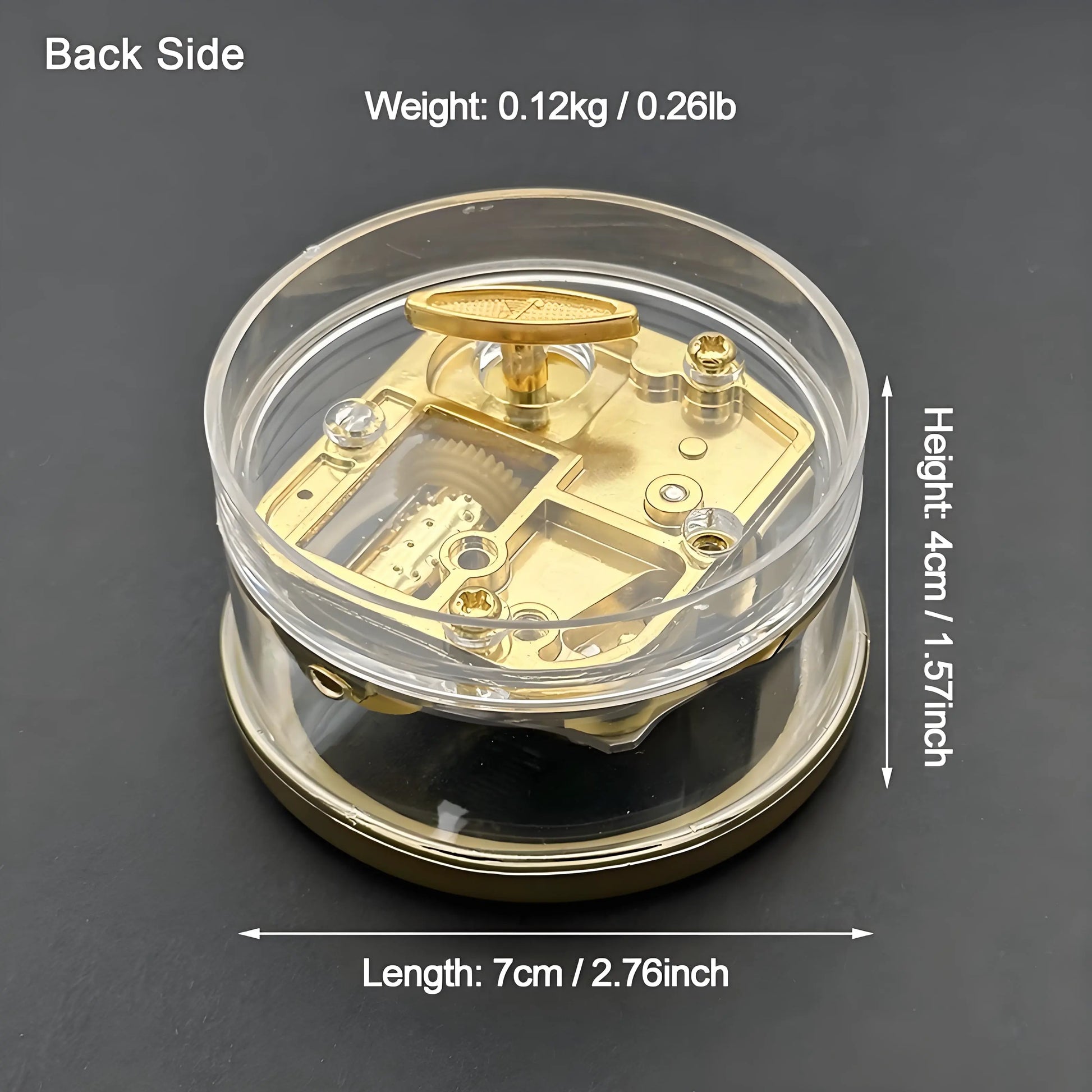 Vintage mini wind-up music box with clear acrylic shell showing gold-plated mechanical movement